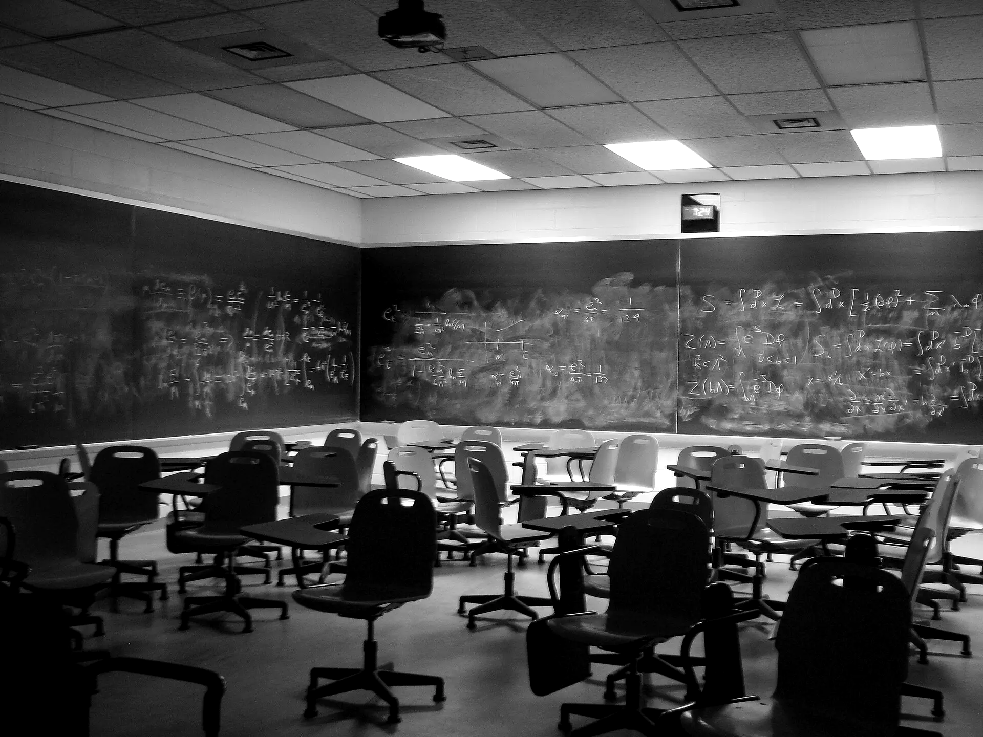 Leeg leslokaal met volgeschreven schoolborden en stoelen met klaptafel