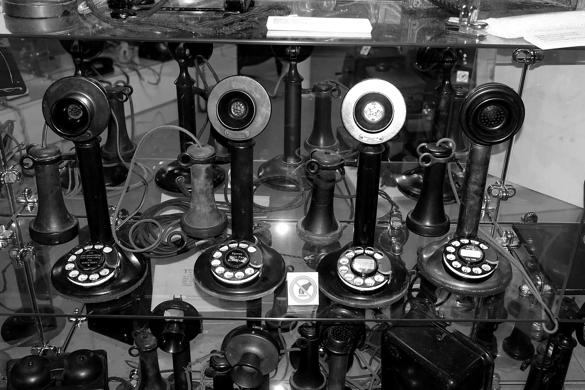 Vitrine met oude staande telefoons met draaischijf